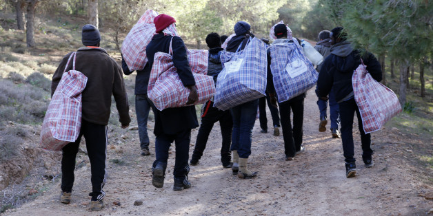 In this photo dated Saturday, Feb. 14, 2015, migrants head back to their mountain camp near the coast city of Nador, northern Morocco, carrying bags of food and clothing provided by Asticude, a Moroccan organization involved with immigration issues. Moroccan security forces raided a makeshift mountain camp and arrested hundreds of illegal migrants in a crackdown aimed at halting the constant attempts to storm Spain's North African enclave of Melilla. (AP Photo/Abdeljalil Bounhar)