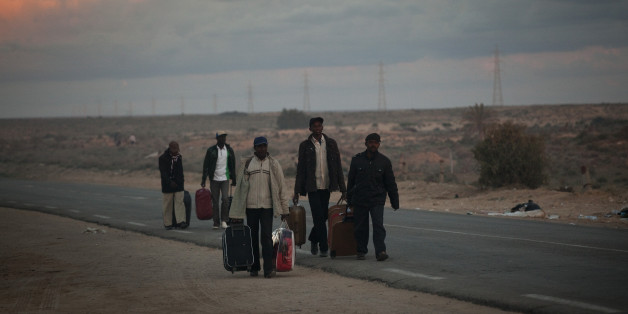 Men from Ghana, who used to work in Libya and fled the unrest in the country, carry their belongings as they arrive in a refugee camp after crossing from Libya at the Tunisia-Libyan border, in Ras Ajdir, Tunisia, Tuesday, March 22, 2011. (AP Photo/Emilio Morenatti)