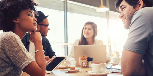 Portrait of group of young people sitting at a cafe and discussing work. Young men and women at coffee shop for startup meeting.