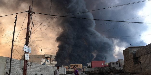 QAYYARAH, IRAQ - OCTOBER 21: Local men pause as an oil field that was set on fire by retreating ISIS fighters ahead of the Mosul offensive burns behind him on October 21, 2016 in Qayyarah, Iraq. Several hundred Iraqi families have been made to leave their homes for Mosul by Islamic State fighters as the UN warns they could be used as human shields. ISIS have attacked Kirkuk today as Kurdish and Iraqi forces, backed by a coalition including Britain and the U.S.A continue their offensive to retake