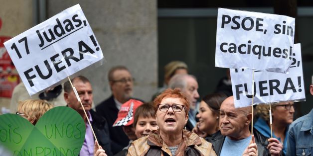 A PSOE supporter holds placards reading '17 Judas out' 'PSOE without chiefs' outside the Spanish Socialist Party (PSOE) headquarters in Madrid during an extraordinary meeting of the PSOE Federal Committee, on October 23, 2016.Spain's embattled Socialists gather today for a crunch strategy meeting expected to see the party lift its veto on a minority conservative government and finally unblock the country's ten-month political deadlock. / AFP / GERARD JULIEN (Photo credit should read GERAR