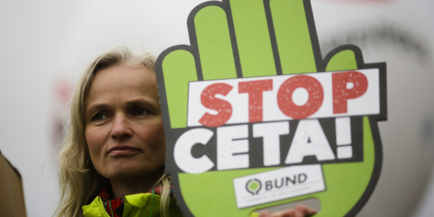 A demonstrator holds a poster against the Comprehensive Economic and Trade Agreement, CETA, during a protest in front of the chancellery in Berlin, Wednesday, Oct. 12, 2016. The Federal Constitutional Court held a hearing Wednesday considering calls from opponents of a European Union-Canada trade deal for an injunction aimed at putting the signing of the accord on ice. (AP Photo/Markus Schreiber)
