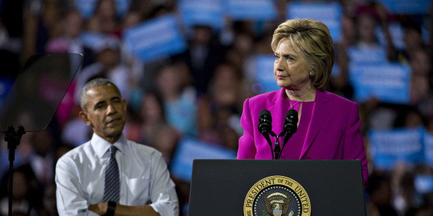 Hillary Clinton, presumptive 2016 Democratic presidential nominee, pauses while speaking as U.S. President Barack Obama, left, listens during a campaign rally at the Charlotte Convention Center in Charlotte, North Carolina, U.S., on Tuesday, July 5, 2016. Obama, making his debut campaign appearance on Clinton's behalf, flew with her on Air Force One as a show of unity and power hours after the FBI director called Clinton's handling of sensitive e-mails as Secretary of State extremely careless. P