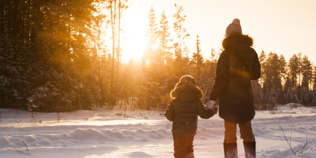 Mother and son walking in snowy forest clearing