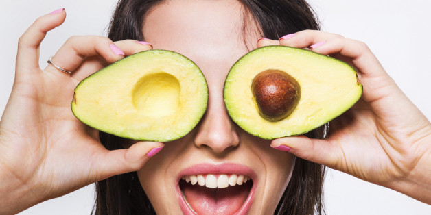 Beauty model holding avocado halves over her eyes