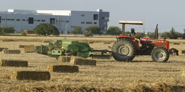 A tractor pulls a hay baler after reaping wheat at a field in Tunis June 18, 2014. REUTERS/Zoubeir Souissi (TUNISIA - Tags: AGRICULTURE SOCIETY)