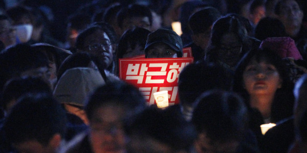 A protester holds a placard and a candle during a rally, calling for South Korean President Park Geun-hye to step down in downtown Seoul, South Korea, Wednesday, Nov. 2, 2016. South Korean prosecutors requested an arrest warrant for a longtime friend of Park on Wednesday over allegations of influence-peddling and other activities that have triggered a huge political scandal that threatens Park's leadership. The placard reads: "Park Geun-hye should step down." (AP Photo/Ahn Young-joon)