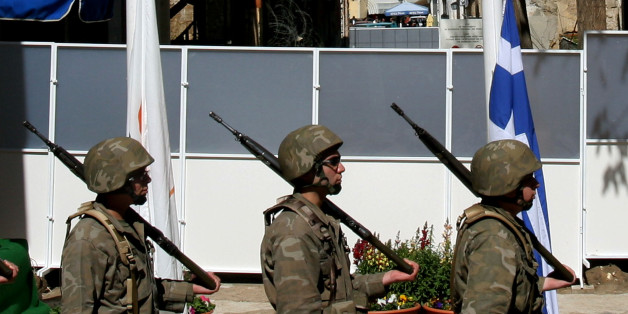 Cypriot soldiers stand with their guns in front of a temporary barrier after a wall was removed from an outpost at the UN buffer zone (Green Line) that divided the Greek and Turkish Cypriot, seen in the background, controlled areas in Ledras street in the divided capital Nicosia, Cyprus, Friday March 9, 2007. Greek Cypriots early Friday demolished a wall along the boundary that splits Europe's last divided capital, Nicosia, in a dramatic and unannounced gesture officials hope will kick-start progress toward reconciling deep and longstanding divisions on the Mediterranean island, Europe's last divided country. (AP Photo/Petros Karadjias)