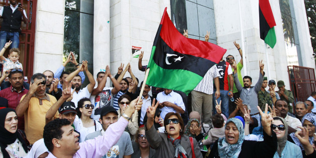 Libyan refugees in Tunisia celebrate after hearing news that Libyan leader Muammar Gaddafi was killed in Sirte, outside their embassy in Tunis October 20, 2011. Gaddafi was killed on Thursday as Libya's new leaders declared they had overrun the last bastion of his long rule, sparking wild celebrations that eight months of war may finally be over. Details of the death near Sirte of the fallen strongman were hazy but it was announced by several officials of the National Transitional Council (NTC) and backed up by a photograph of a bloodied face ringed by familiar, Gaddafi-style curly hair. REUTERS/Zoubeir Souissi (TUNISIA - Tags: CIVIL UNREST POLITICS)