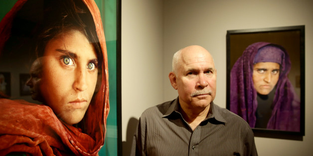 US photographer Steve McCurry poses next to his photos of the 'Afghan Girl' named Sharbat Gula at the opening of the 'Overwhelmed by Life' exhibition of his work at the Museum for Art and Trade in Hamburg, northern Germany on June 27, 2013. The exhibition comprises some 120 photographs taken between 1980 and 2012 in countries such as Afghanistan, the United States, Pakistan, India, Tibet, Kashmir, Cambodia, Indonesia, Burma and Kuwait. AFP PHOTO / DPA / ULRICH PERREY GERMANY OUT RESTRICTED TO ED
