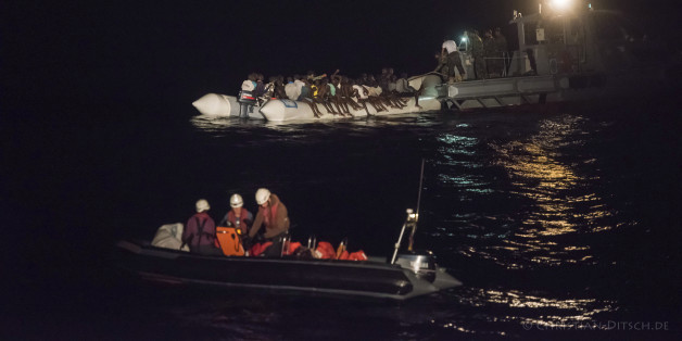 In this Oct. 21, 2016 picture provided by Sea-Watch aid group, refugees sit in a inflatable boat, background left, while a speedboat, labelled as Libyan Coast Guard, background right, and Sea-Watch members in a boat foreground arrive off the Libyan coast in the Mediterranean Sea. The German aid group Sea-Watch urged the European Union on Tuesday Oct. 25, 2016 to reconsider its plans to train Libyan forces to conduct sea rescue operations after a vessel labeled as belonging to the country's coast guard attacked the dinghy full of migrants last week. Dozens of people were feared dead in the incident. (Christian Ditsch/Sea-Watch via AP)