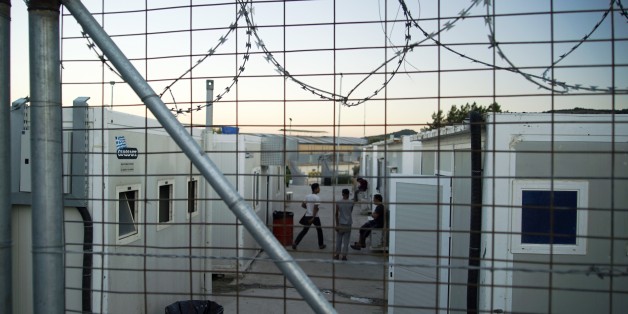 People sit outside container houses at a refugee camp on the northeastern Greek island of Chios, Thursday, Sept. 29, 2016. More than 3,500 refugees and migrants are stuck on Chios island, since the European border closures earlier this year. (AP Photo/Mstyslav Chernov)