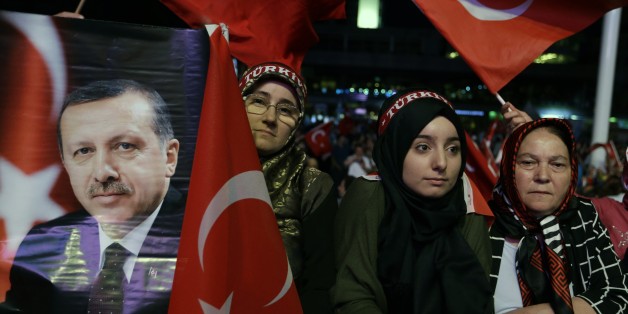 A woman holds a photograph of Turkish President Recep Tayyip Erdogan as others wave flags of their country during an anti coup rally at Taksim square in Istanbul, Wednesday, Aug. 10, 2016. The failed coup left more than 270 people dead and about 18,000 people have been detained or arrested. (AP Photo/Thanassis Stavrakis)