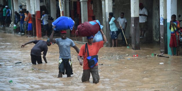 Haitian men navigate a partially flooded street during a seasonal storm on November 5, 2016 in the commune of Jeremie, southwestern Haiti, one of the cities hit hard by Hurricane Matthew.One month ago, on October 4, Haiti was hit by Hurricane Matthew where at least 546 people were killed, packing winds of 145 miles (230 kilometers) per hour. / AFP / HECTOR RETAMAL (Photo credit should read HECTOR RETAMAL/AFP/Getty Images)