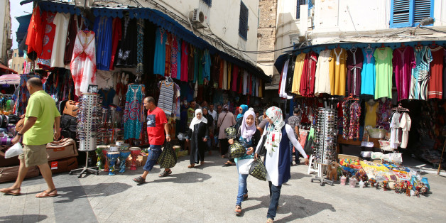 People walk past a clothes shop in souk of the old quarter in Tunis, Tunisia, August 10, 2016. REUTERS/Zoubeir Souissi