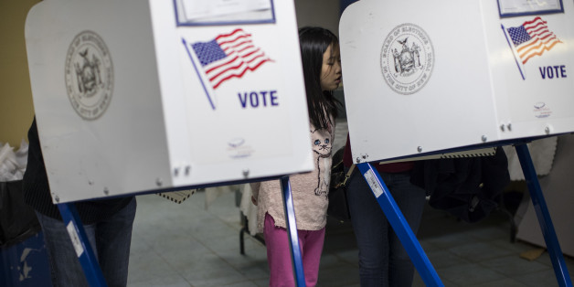 CORRECTS TO QUEENS BOROUGH, NOT BROOKLYN - Helen Chiu, center, watches as her mom Yvonne Chiu, right, and her father Joseph S Chiu, left, mark their ballots at a polling station in Flushing, the Queens borough of New York, Tuesday, Nov. 8, 2016. Born in southwestern China's Fujian province, Yvonne and Joseph immigrated to the United States 20 years ago, and this is their first time voting. (AP Photo/Alexander F. Yuan)