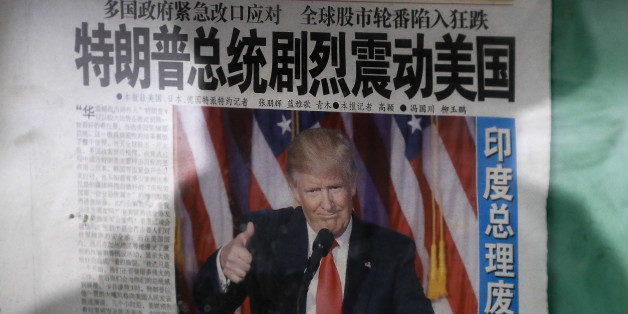 A man is reflected on a glass as he reads a Chinese newspaper with a photo of U.S. President-elect Donald Trump, displayed on a newspaper board in Beijing, Thursday, Nov. 10, 2016. Donald Trump's promise to put America first helped propel him to the U.S. presidency. But he also unleashed uncertainty on the global economy by skewering trading partners and offering few specifics that might calm allies or businesses. The headline reads "President Donald Trump delivers a mighty shock to America." (AP Photo/Andy Wong)