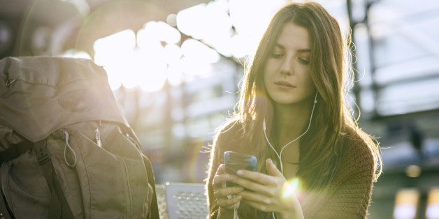 Young backpacker checking emails on smart phone while waiting for her flight