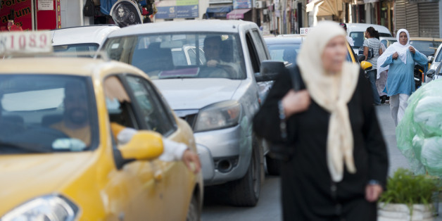 TUNIS, TUNISIA - AUGUST 14: Women go their way next to cars in the Old Quarter in Tunis, Tunisia, on August 14, 2013 in Tunis, Tunisia. (Photo by Michael Gottschalk/Photothek via Getty Images)