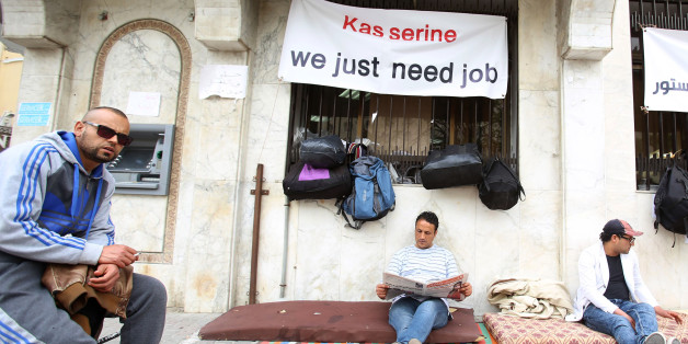 Mohamed Zied el Harizi (C), 37, an unemployed graduate from the city of Kasserine, reads a newspaper as he takes part in a sit-in protest near the Ministry of Vocational Training and Employment demanding the government to provide them with job opportunities in Tunis, Tunisia, April 1, 2016. REUTERS/Zoubeir Souissi