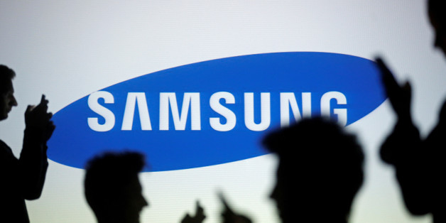 People are silhouetted as they pose with mobile devices in front of a screen projected with a Samsung logo, in this picture illustration taken in Zenica October 29, 2014. REUTERS/Dado Ruvic/Illustration/File Photo