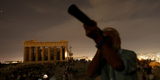 A Greek man looks through his telescope at the full moon as at the backround is seen the ancient temple of Parthenon at Acropolis hill, in Athens on Wednesday, Aug. 9, 2006. Many archaeological sites in Greece were open for the public Wednesday night for the full moon. (AP Photo/Petros Giannakouris)