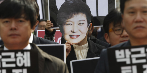 A South Korean protester wearing a mask of South Korean President Park Geun-hye marches during a rally calling for Park to step down in Seoul, South Korea, Friday, Nov. 18, 2016. South Korea's parliament on Thursday passed a law that would allow a special prosecutor to investigate a corruption scandal threatening the presidency of Park. The cards read "Park Geun-hye should step down." (AP Photo/Ahn Young-joon)