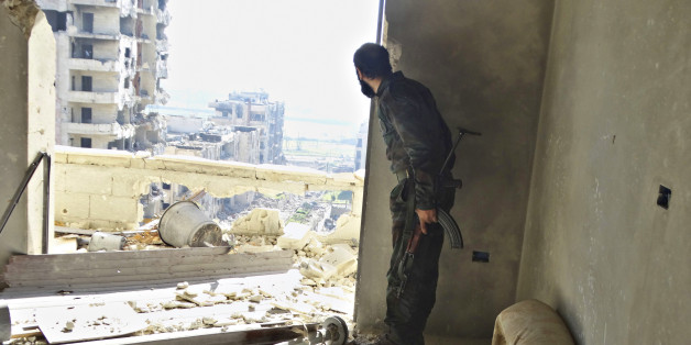 A rebel fighter stands with his weapon inside a damaged building in the northwestern Homs district of Al Waer January 18, 2015. REUTERS/Stringer (SYRIA - Tags: CIVIL UNREST CONFLICT SOCIETY)