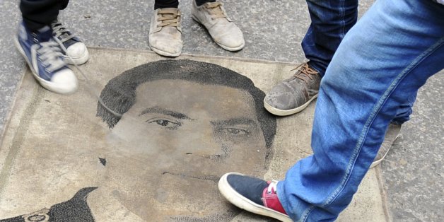 Protestors step on a carpet depicting ousted Tunisian President Zine El Abidine Ben Ali during a demonstration to mark the third anniversary of his departure, Tuesday, Jan. 14, 2014. Three years ago, mass public protests ousted Tunisian President Zine el-Abidine Ben Ali from office. (AP Photo/Hassene Dridi)