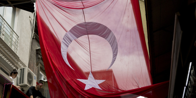 A man tries to unwrap a giant Turkish flag at Grand bazaar, one of the largest and oldest covered markets in the world, in Istanbul, Monday, July 18, 2016. The European Union and the United States expressed alarm Monday with Turkey's response to a failed coup, telling the NATO member and EU aspirant that it must uphold democracy and human rights as it pursues the military officers and anyone else involved in the plot. (AP Photo/Petros Giannakouris)