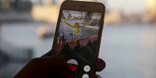 FILE - In this July 25, 2016, file photo, a fan maneuvers his smartphone as he plays "Pokemon Go" in Hong Kong. Japanese video game maker Nintendo Co. slashed its operating profit and sales forecasts for this fiscal year, despite the global success of âPokemon Go.â The maker of Super Mario games and the Wii U console said Wednesday, Oct. 26, 2016, that it booked a 62.7 billion yen ($601.7 million) gain in April-September from its sale of the Seattle Mariners Major League Baseball team.