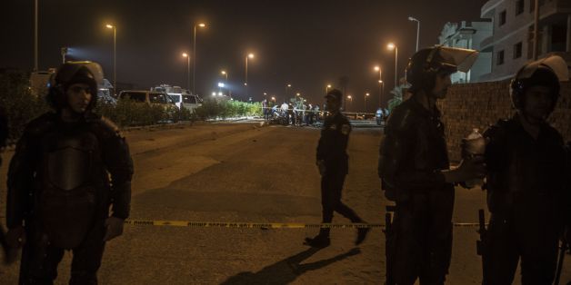 Egyptian riot policemen stand guard as officials inspect the wreckage of a car bomb that exploded in a Cairo suburb after Egypt's deputy prosecutor general drove by late on September 29, 2016, wounding a passerby.A bomb in a car parked on the side of the road exploded after deputy prosecutor general Zakareya Abdel Aziz drove past in an upmarket district of eastern Cairo, the interior ministry said. / AFP / KHALED DESOUKI (Photo credit should read KHALED DESOUKI/AFP/Getty Images)