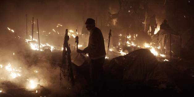 People try to extinguish fires with buckets at the moria migrants camp on the island of Lesbos early on November 25, 2016.
Angry migrants set fire to a camp on the Greek island of Lesbos after a woman and a six-year-old child died following a gas cylinder explosion, local police said. / AFP / STR (Photo credit should read STR/AFP/Getty Images)