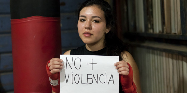 Javiera Paz González, seventeen-year-old amateur boxer from the School of Carlos "Látigo" Uribe, holds in her hands a sign saying "No to violence" on the International Day of Non-Violence Against Women in Osorno, Chile on 24 November 2016. (Photo by Fernando Lavoz/NurPhoto via Getty Images)