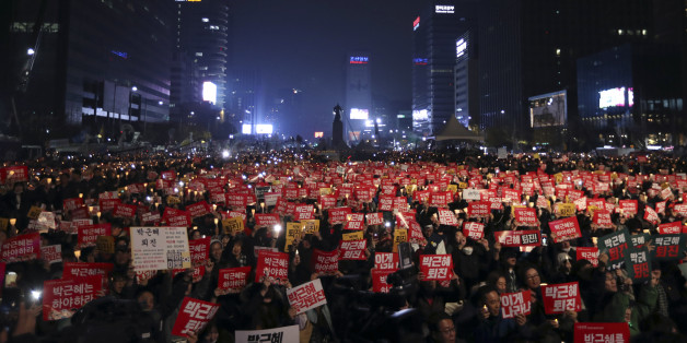 South Korean protesters hold up candles and placards during a rally calling for South Korean President Park Geun-hye to step down in Seoul, South Korea, Saturday, Nov. 19, 2016. For the fourth straight Saturday, masses of South Koreans filled major avenues in downtown Seoul demanding an end to the presidency of Park, who prosecutors plan to question soon over an explosive political scandal. The letters read "Park Geun-hye, Step Down." (AP Photo/Lee Jin-man)