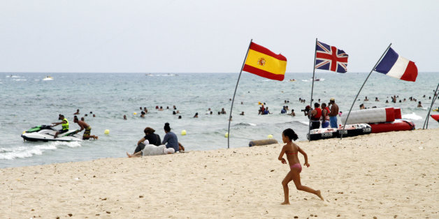 In this Aug. 9, 2015 photo, a young girl runs past European flags on a crowded beach in Hammamet, Tunisia. The jet skis roar by the shore and the water is full of splashing children along the Tunisian Riviera, where despite the deadly attack that killed 38 tourists in June, the beaches are still full _ for now. Europeans have abandoned this North African country, leaving just local Tunisian beach-goers and visiting Algerians. But they will be gone by monthâs end, and then the real pain for the countryâs all-important tourism industry will begin. (AP Photo/Paul Schemm)