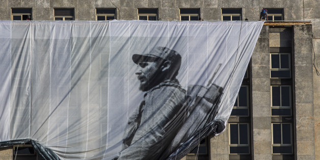Men hang a giant banner with a picture of Cuba's late leader Fidel Castro as a young revolutionary, from the Cuban National Library building in Havana, Cuba, Sunday, Nov. 27, 2016. Cuba's government declared nine days of national mourning after Castro died Friday and this normally vibrant city has been notably subdued. (AP Photo/Desmond Boylan)