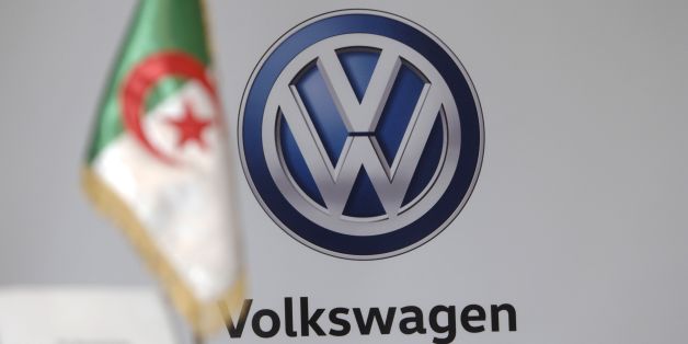 The Algerian national flag is seen in front of a German carmaker Volkswagen (VW) logo during a meeting to sign a protocol agreement for the construction of a plant in the industrial zone of Sidi Khettab, on November 27, 2016 in the capital Algiers. Volkswagen and Algerian group Sovac agreed to launch shortly a car assembly plant in Relizane, some 320km west of Algiers. / AFP / RYAD KRAMDI (Photo credit should read RYAD KRAMDI/AFP/Getty Images)