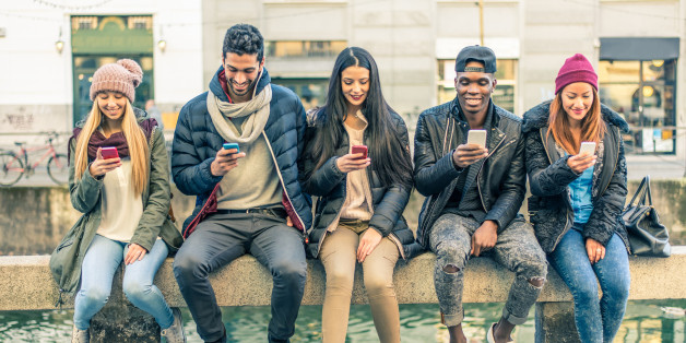 Multicultural group of friends using cellphones - Students sitting in a row and typing on the smartphones