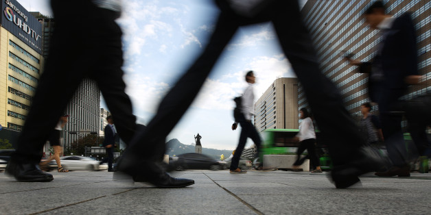 Morning commuters and pedestrians walk through Gwanghwamun square in Seoul, South Korea, on Friday, Aug. 28, 2015. South Korea is scheduled to release second-quarter gross domestic product figures on Sept. 3. Photographer: SeongJoon Cho/Bloomberg via Getty Images