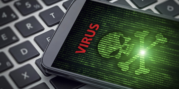 Virus alert on the screen of smartphone on laptop computer. Skull of death on data flowing background. Selective focus on screen of the phone.