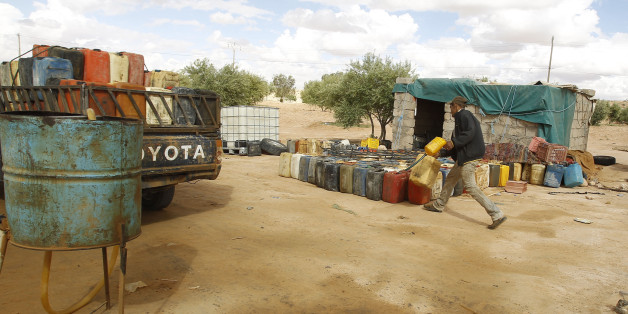 A man fills containers with gasoline at the southern Libya-Tunisia border crossing in Dehiba, April 17, 2012. In the absence of proper border controls after uprisings which ousted autocratic leaders in both Tunisia and Libya, smugglers plying unmarked desert routes on the Tunisian-Libyan border are becoming ever bolder, and disputes over smuggling routes are becoming ever more violent. Picture taken April 17, 2012. To match Feature TUNISIA-SMUGGLING/ REUTERS/Zoubeir Souissi (TUNISIA - Tags: CRIME LAW SOCIETY)