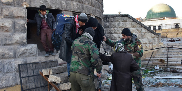 Syrian residents fleeing the violence in the eastern rebel-held parts of Aleppo are helped by pro-government forces as they evacuate from their neighbourhoods through the Bab al-Hadid district after it was seized by the regime, on December 7, 2016.
In the face of a blistering assault by forces loyal to President Bashar al-Assad, the rebels were reported to have retreated from all of Aleppo's Old City, the latest in a string of territorial losses. / AFP / GEORGE OURFALIAN (Photo credit should read GEORGE OURFALIAN/AFP/Getty Images)