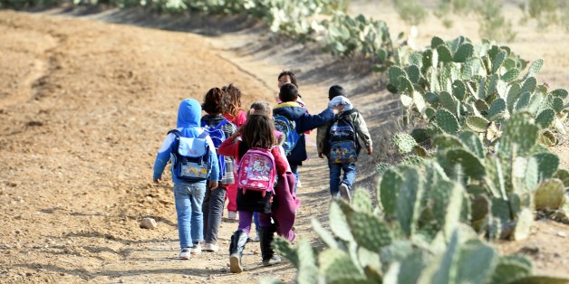 TO GO WITH AFP STORY BY INES BEL AIBA - Tunisian children carry their schoolbags as they are heading to school in the impoverished village of Daouar Slatniya which lies at the bottom of the Mount Mghilla on December 15, 2015 between Kasserine (some 360 kilometres south of Tunis) and the central town of Sidi Bouzid. AFP PHOTO / FETHI BELAID / AFP / FETHI BELAID (Photo credit should read FETHI BELAID/AFP/Getty Images)