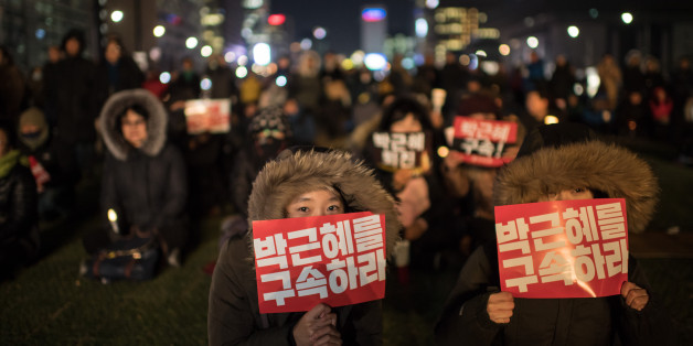TOPSHOT - A woman hold a placard reading 'Arrest Park Geun-Hye' during a small rally following the impeachment of President Park Geun-Hye, in central Seoul on December 9, 2016.South Korean lawmakers voted to impeach President Park Geun-Hye, stripping away her sweeping executive powers over a corruption scandal and opening a new period of national uncertainty. / AFP / Ed JONES (Photo credit should read ED JONES/AFP/Getty Images)