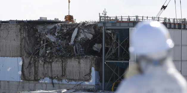 A member of the media, wearing a protective suit and a mask, looks at the No. 3 reactor building at Tokyo Electric Power Co's (TEPCO) tsunami-crippled Fukushima Daiichi nuclear power plant in Okuma town, Fukushima prefecture, Japan February 10, 2016. REUTERS/Toru Hanai