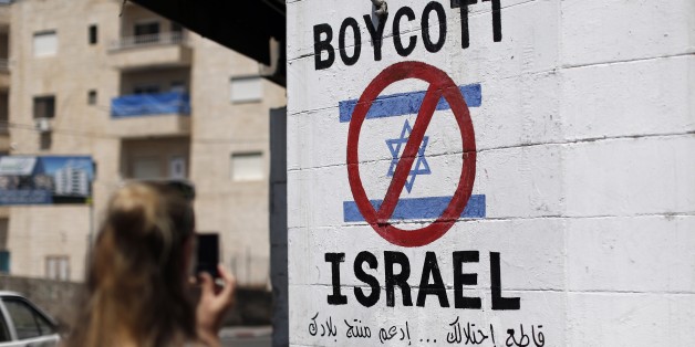 A tourist photographs a sign painted on a wall in the West Bank biblical town of Bethlehem on June 5, 2015, calling to boycott Israeli products coming from Jewish settlements. The international BDS (boycott, divestment and sanctions) campaign, that pushes for a ban on Israeli products, aims to exert political and economic pressure over Israel's occupation of the Palestinian territories in a bid to repeat the success of the campaign which ended apartheid in South Africa. AFP PHOTO / THOMAS COEX