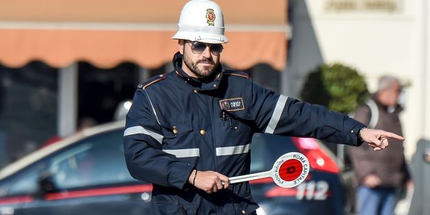 A police officer controls cars and scooters during the limited traffic day, in centeral Rome, on December 29, 2015. A second day with limited traffic of odd and even car plate numbers was enforced in the hope of lowering air pollution. A lack of rainfall has led pollution levels to climb in recent weeks, and has prompted the administration of Rome, to appeal to drivers to respect the rules. / AFP / ANDREAS SOLARO (Photo credit should read ANDREAS SOLARO/AFP/Getty Images)