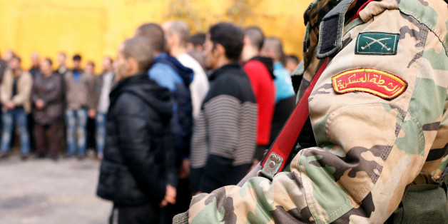 A member of the government military police stands guard as men, who were evacuated from the eastern districts of Aleppo, are being prepared to begin their military service at a police centre in Aleppo, Syria December 11, 2016. REUTERS/Omar Sanadiki