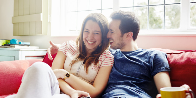 Young couple laugh together as they relax on sofa